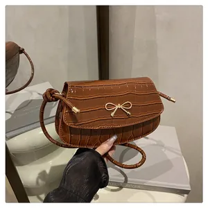 Detailed macro view of the brown crocodile pattern leather bag with a gold bow buckle