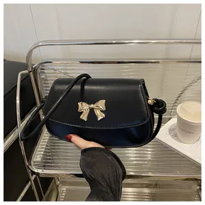 Détail d'un sac bandoulière en cuir noir avec un fermoir nœud métallique doré élégant