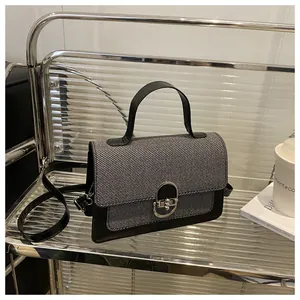 Detail of grey textured fabric crossbody bag with silver horseshoe metal lock and black handle