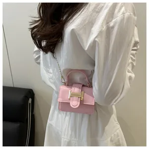Close-up of pink glossy mini crossbody bag with gold chain strap and metal buckle