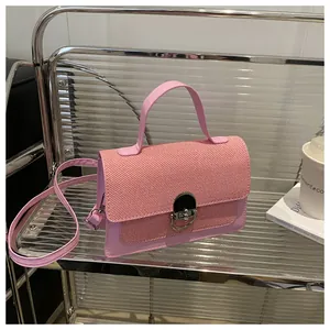 Detail of pink leather handbag with woven flap and metallic clasp on a modern glass shelf