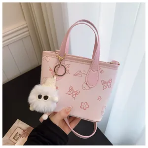 Detail of pink PU leather bucket bag with butterfly prints and a furry monster charm