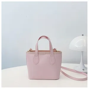 Detail view of pink leather bucket bag texture and handle on a minimalist white desk