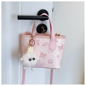 Detail view of pink bucket bag featuring butterfly prints and a fuzzy charm accessory