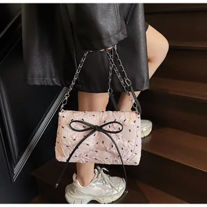 Detailansicht der rosa Schultertasche mit schwarzen Schleifen und silberner Kette