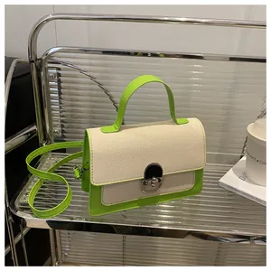 Detail of a contrast color crossbody bag featuring woven texture and green leather trim