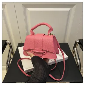 Close-up of pink litchi grain leather mini handbag with gold metal clasp details