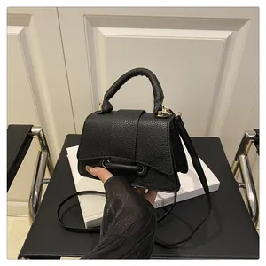 Detail view of black lychee grain handbag with gold metal hardware and leather ring buckle