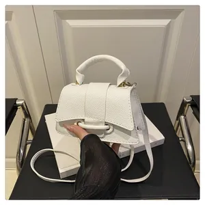 Detail of white pebble grain leather mini bag with curved handle and trapezoidal shape