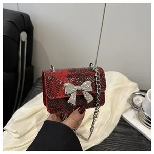Detail of red snake-pattern mini bag with silver bow buckle and elegant metal chain