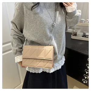 Fashionable beige quilted crossbody bag with silver chain strap worn by a model