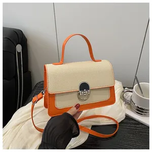 Detail of orange leather and beige woven handbag with silver metal twist lock closure