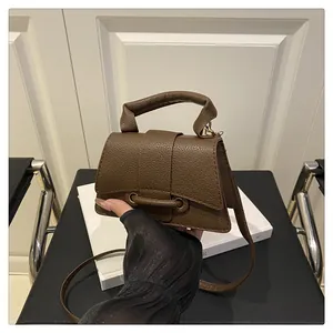 Detail view of brown lychee pattern leather handbag with sturdy handle and strap