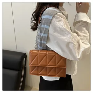 Detailed side view of brown quilted crossbody bag with silver chain strap on model