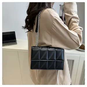 Detail of black crossbody bag with triangle quilted pattern and silver chain strap