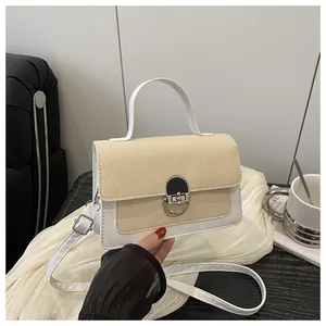 Close-up of small crossbody bag featuring beige straw lid and white leather body