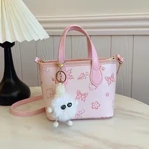 Pink printed bucket bag with floral patterns and plush charm on marble surface