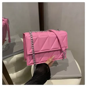 Detail of pink small square bag with geometric triangle embossing and silver chain strap