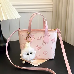 Pink printed crossbody bucket bag with cartoon motifs and fluffy monster charm
