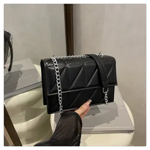 Detail of black quilted leather crossbody bag with silver chain strap and diamond pattern