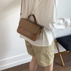Detail view of brown patchwork crossbody bag with woven texture on a model shoulder