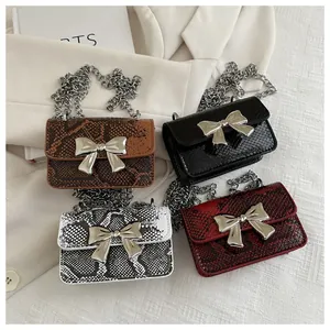 Close-up of mini square bags with snake pattern, silver bow detail, and chain straps