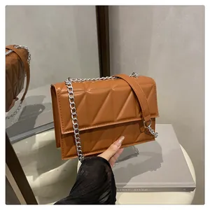 Detailed view of quilted caramel brown crossbody bag with silver chain strap and mirror reflections