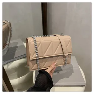 Detail of beige quilted shoulder bag with geometric embossing and silver chain strap