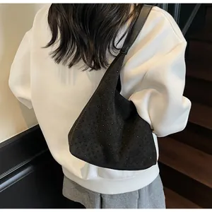 Detail of black suede shoulder bag with dense rivet studs worn over a white hoodie
