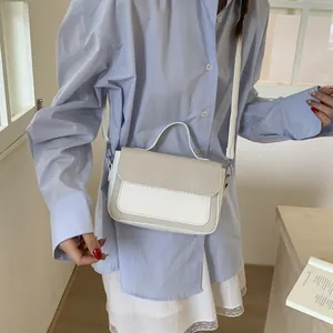 Detail showing woman wearing beige patchwork woven crossbody bag with leather texture