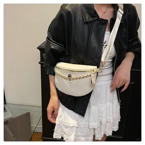 Detail of white crossbody bag with skull embossing and gold chain on a model