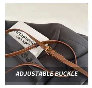Detail of adjustable golden metal buckle on a brown leather handbag shoulder strap