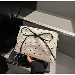 Detailansicht der weißen Tasche mit schwarzer Schleife auf kunstvollen Büchern