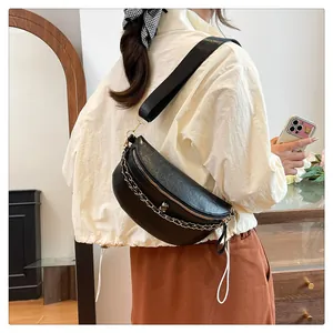 Detail of black crossbody chest bag with skull embossing and silver metal chain strap