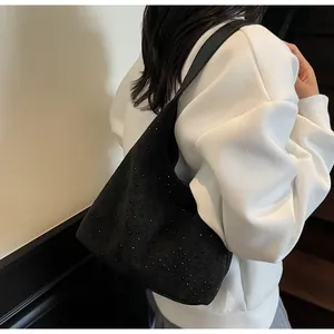 Close-up of black suede hobo bag with sparkling rhinestones worn on shoulder