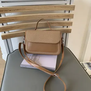 Detail of a brown patchwork mini handbag with woven texture and smooth leather finish