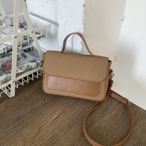 Detailed close-up of woven fabric and smooth leather texture on brown crossbody handbag
