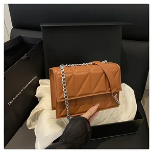 Close-up of caramel quilted leather crossbody bag with silver chain strap in luxury gift box