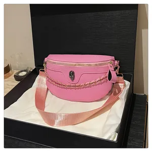Detailed view of pink leather chest bag featuring skull embossing and gold chain detail