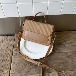 Detail of a brown woven patchwork crossbody bag with smooth leather and silver hardware