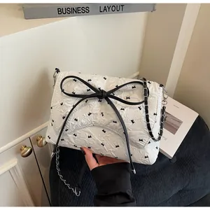 Detail einer weißen Stepptasche mit schwarzen Schleifen-Stickereien und silberner Kette