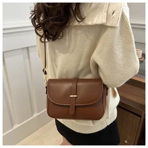 Close-up of brown vegetable tanned leather shoulder bag with sleek metal bar buckle closure