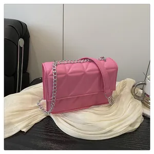 Detail of pink quilted crossbody bag with silver metal chain strap and flap closure