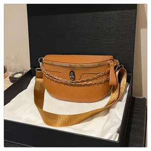 Detailed view of tan skull embossed crossbody bag with gold chains and metallic skull charm