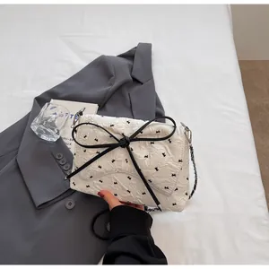 Nahaufnahme des beigen Jacquard-Stoffs mit schwarzen Schleifen und edlem Kettenriemen