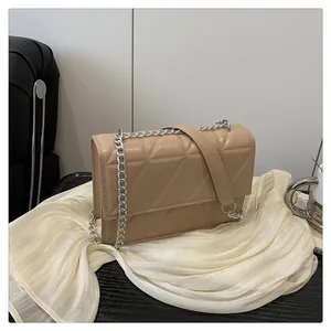 Detail of beige quilted crossbody bag featuring silver chain strap and geometric stitching