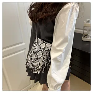 Detailed shot of black and white snake skin patterned crossbody bag with long side tassels