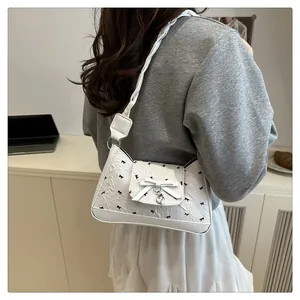 Détail du sac sous l'aisselle en cuir PU blanc avec imprimé nœud et breloque cœur