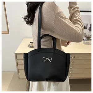 Detail of black matte leather tote bag with elegant silver bow metallic buckle