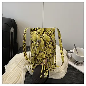 Close-up of yellow snakeskin pattern handbag with long fringe details and crossbody strap